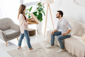 Wall Mural - high angle view of young couple with pizza in disposable box at home