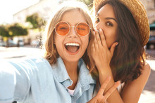 Portrait Of Two Pretty Cute Teenagers Blond And Brunette Models Share Secrets, Gossip. Surprise Face, Emotions, Best Friends Wearing Stylish Outfit And Taking Selfie On The Street Background
