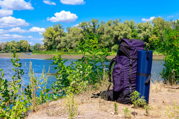 Tourist backpack near a river at summer. Hike concept