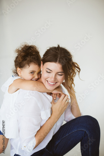 Fotomural Cute little daughter happily hugging beautiful mother while spen