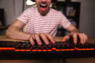 Wall Mural - Cropped image of Screaming gamer playing video games on computer