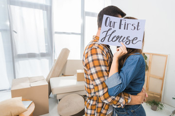 Wall Mural - obscured view of couple kissing behind our first house card at new home