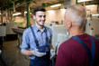 © pressmaster - Happy young worker in overalls and gloves speaking to his mature experienced colleague in workshop