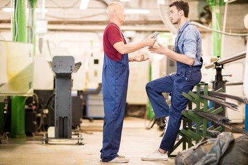 Two contemporary engineers in workwear having hot debates concerning working process