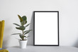 Poster A2 in black frame in nordic stylish modern interior, yellow armchair, ficus, living room. Empty space for design layout..