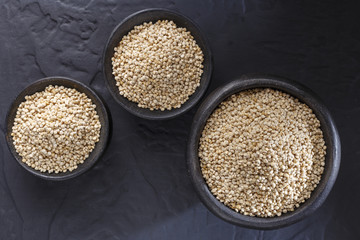 Wall Mural - Quinoa grains with spoon and bowl on black background