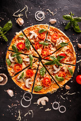 Flat lay with Italian pizza on black background and various ingredients