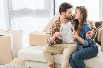 Wall Mural - couple in love with glasses of champagne at new house with cardboard boxes, moving home concept