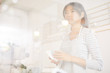 © pressmaster - Young worker of cafeteria standing by cashier counter and preparing drink for client
