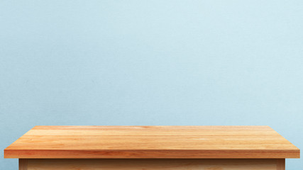 Empty wooden tabletop isolated on blue wall background. For your product placement or montage with focus to the table top in the foreground. Empty pine wooden shelf. shelves