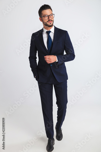 Fotografía relaxed businessman wearing glasses and navy suit walking