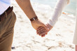 © LIGHTFIELD STUDIOS - partial view of couple holding hands while walking on sandy beach