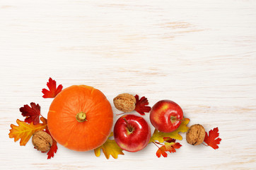 Wall Mural - round pumpkin, apples and walnuts with colorful leaves on wood