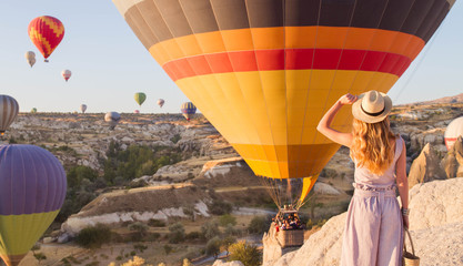 Hipster Traveler with backpack and outspread hands. Enjoying the view of the hot air balloons