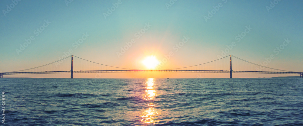 Mackinac Bridge in Michigan at sunset. Horizontal panoramic view of a long steel suspension bridge located in the Great lakes region of North America. - obrazy, fototapety, plakaty 