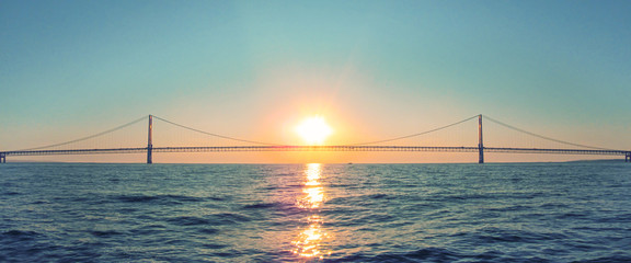 Mackinac Bridge in Michigan at sunset. Horizontal panoramic view of a long steel suspension bridge located in the Great lakes region of North America.