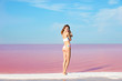 © New Africa - Beautiful woman in swimsuit standing near pink lake on sunny day