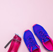 Ultra blue violet pink female sneakers and water bottle on pastel pink background flat lay top view with copy space. Sports shoes, fitness, concept of healthy lifestile, everyday training.