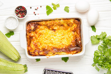 Wall Mural - Fluffy omelet baked with zucchini, kids healthy Breakfast, tasty casserole. On white wooden background, in baking dish