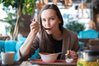 © Руслан Галиуллин - Portrait of a young woman in the interior of the restaurant at the table eating soup with bread, blurred background