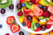 fruit salad with watermelon, strawberry, cherry, blueberry, kiwi, raspberry and peaches in a bowl on white background