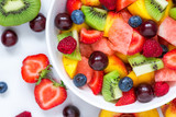 fruit salad with watermelon, strawberry, cherry, blueberry, kiwi, raspberry and peaches in a bowl on white background