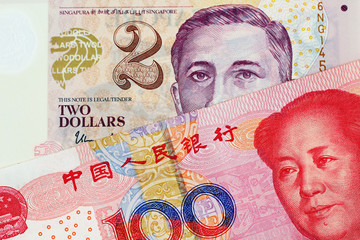 A close up image of a two Singapore Dollar bank note with a hundred Chinese Yuan bank note