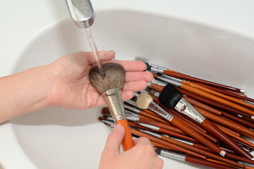 makeup artist is rinsing cosmetic brush by water