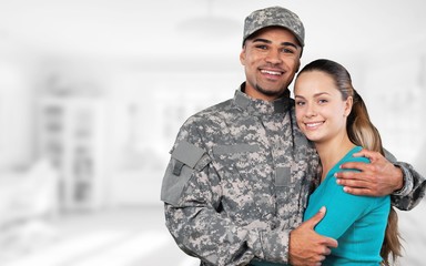 Smiling soldier with his wife standing against  background