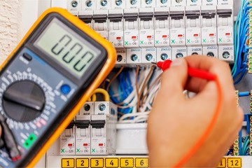 Wall Mural - Hand of an electrician with multimeter probe at an electrical