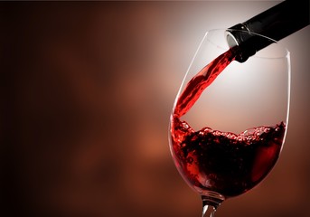 Canvas Print - Red wine pouring in glass on  background