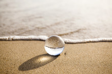 Glass Ball Crystal Clear Reflecting The Sea And Beach In The Morning