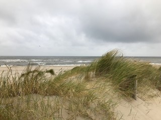 Dutch coastal landscape with North sea, beach, sand, sky, clouds and grass on a cloudy day