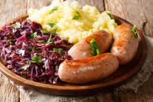 Roasted Sausages With Red Sauerkraut And Potatoes Close-up On A Plate On A Table. Horizontal