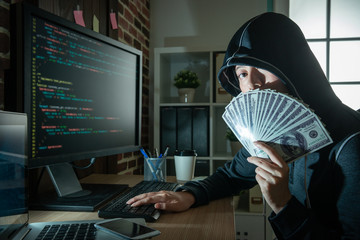 hacker hiding her face with money spread.