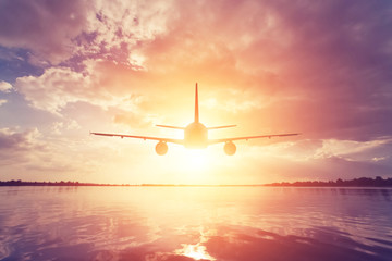 Airplane flying over the sea during sunset