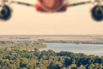 Wall Mural - Silhouette of an airplane flying over a forest and a river