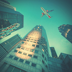 Wall Mural - Airplane flying over skyscrapers, view of a bottom-up. Toned