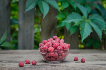 Raspberry in a glass bowl on a wooden surface