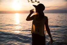 Silhouetted Woman Drinking A Glass Of Rosé Wine And Wearing A See-through Summer T-Shirt At Sunset.