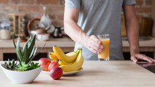 Healthy Eating Habit. Unrecognizable Man Holding A Glass Of Freshly Squeezed Fruit Juice. Natural Organic Banana And Nectarine Drink. Balanced Diet And Nutrition.