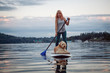 Girl with a dog on a paddle board during a vibrant summer sunset. Taken in Deep Cove, North Vancouver, BC, Canada.