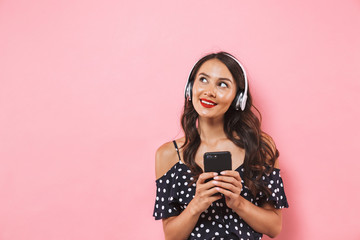 Poster - Pensive smiling brunette woman in dress and headphones listening music