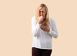 © luismolinero - Middle age blonde woman with white shirt is suffering with cough and feeling bad on isolated ocher background