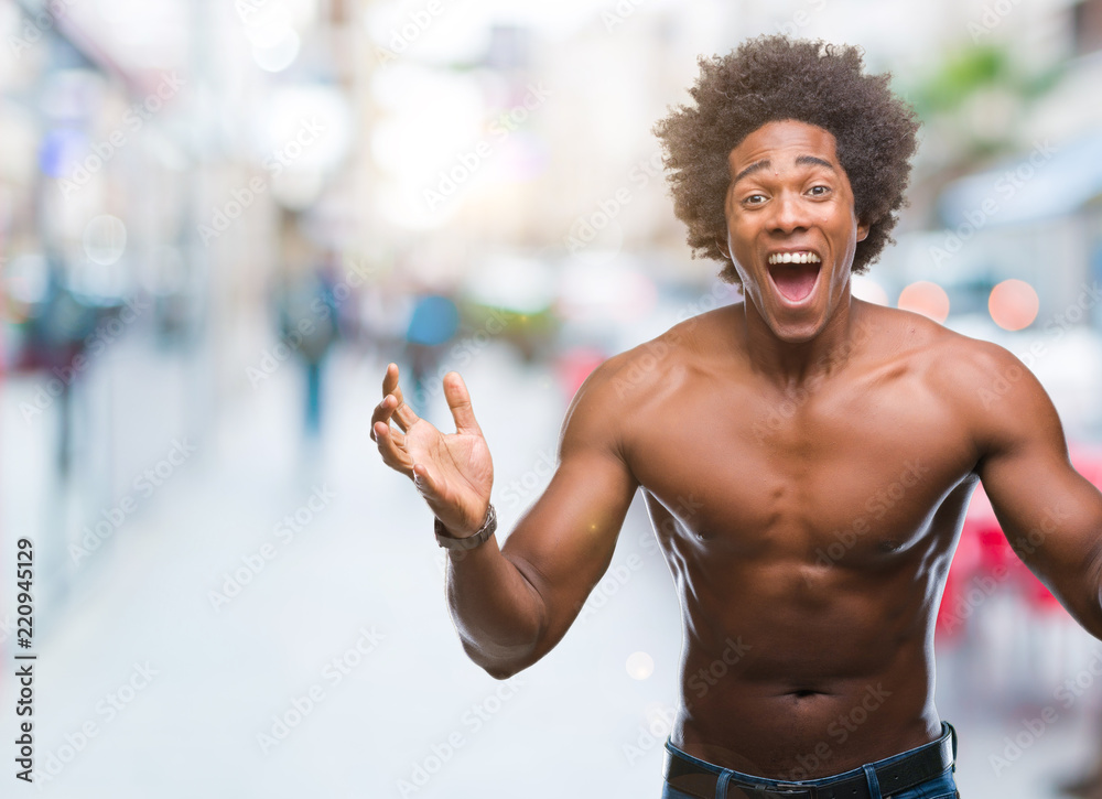 Afro american shirtless man showing nude body over isolated background celebrating crazy and
