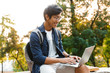 © Drobot Dean - Pleased asian male student in eyeglasses using laptop computer