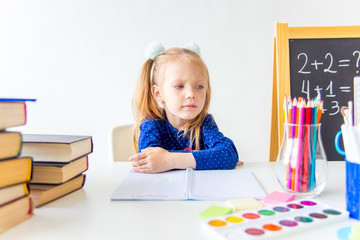 Happy cute industrious child is sitting at a desk indoors