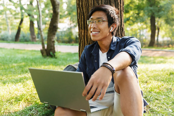 Sticker - Happy asian male student in eyeglasses with laptop computer