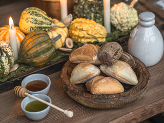 Table setting for Thanksgiving. Autumn table with pumpkins and candles in the center. Wood bowl with bread and two small bowl with various honey