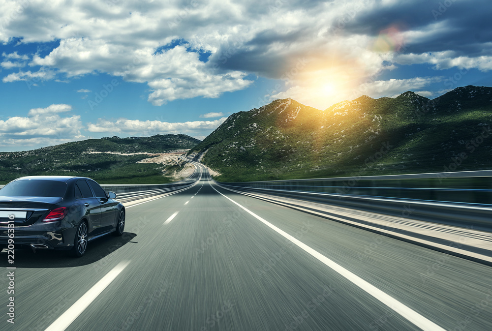 Black car rushing along a high-speed highway in the sun. Stock Photo ...